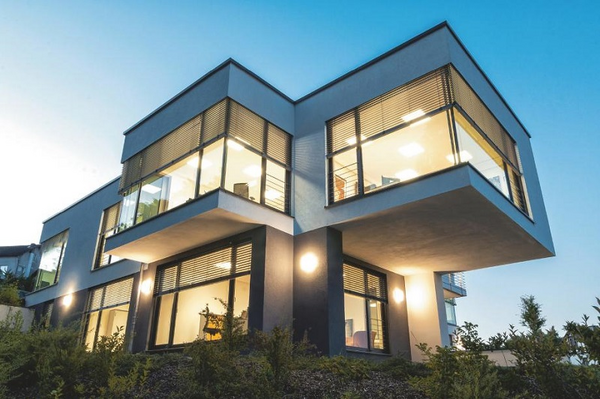 Modernes Architektenhaus mit großen Panoramafenstern und stilvoller Fassadenbeleuchtung.